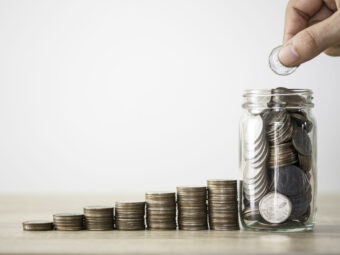 Hand putting coin to saving jar and coins stacking. Money saving